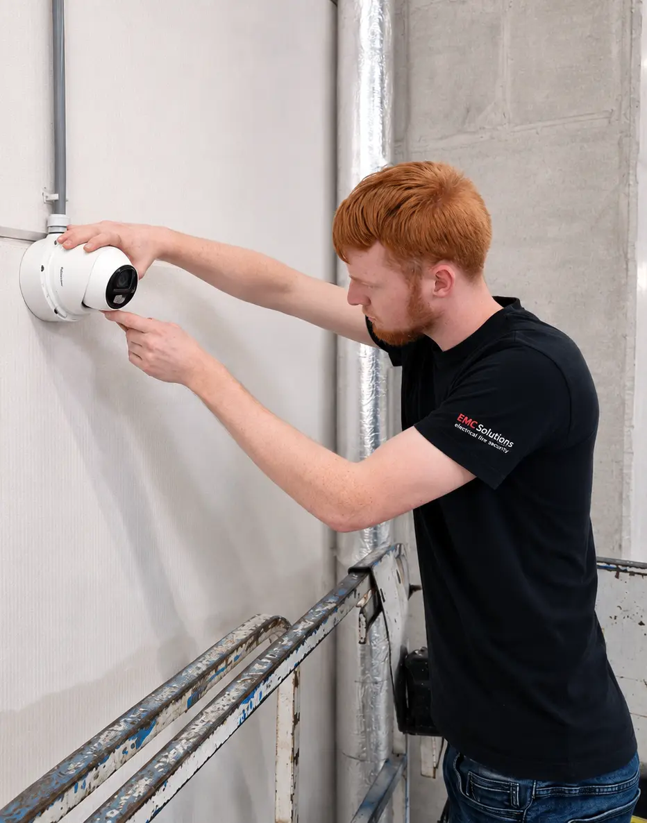 beveiligingscamera-installatie-bedrijf-emc-solutions-specialist Monteur installeert een professionele Hikvision beveiligingscamera bij een bedrijfspand